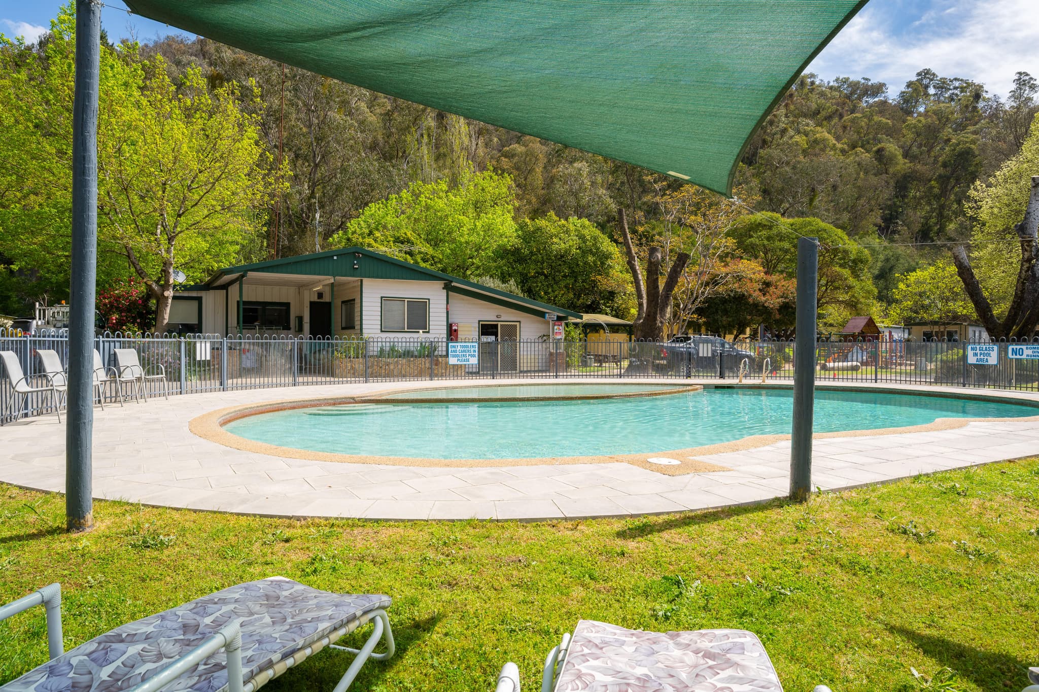 Swimming pool area with shade sail and sun loungers at Bright Accommodation Park, Great Alpine Road, Bright VIC